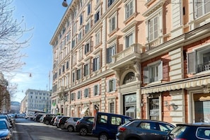 A row of parked cars along a street with a multi-story building featuring classical architecture. - B B Le Suite Di Via Catone (Rome)