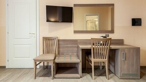 A hotel room with a wooden desk, two chairs, a flat-screen TV mounted above the desk, and a white door. - B&B Le Suite di Via Catone (Rome)