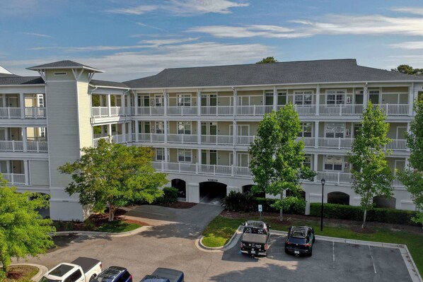 A multi-story hotel with a central courtyard, balconies, and a parking area. - Litchfield Beach 2 Queen Room at Seaside Inn (Pawleys Island)