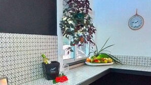 A kitchen with a gas stove, two stools, a potted plant, and a clock on the wall. - Casitas en la Jungla - Luz Tropical (Puerto Viejo de Talamanca)
