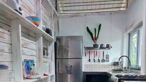 A kitchen with wooden cabinets, a stainless steel refrigerator, a gas stove, and a wooden bench. - Casitas en la Jungla - Luz Tropical (Puerto Viejo de Talamanca)