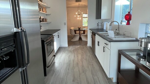 Eine moderne Küche mit Kühlschrank, Backofen und Spüle. Ein Essbereich mit Stühlen und Tisch ist ebenfalls vorhanden.