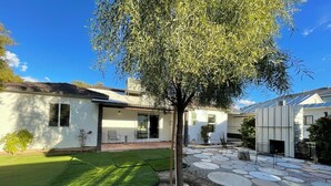 Ein Haus mit Terrasse, Rasen und Baum.