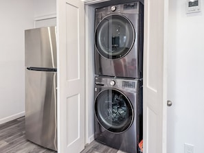 Convenient laundry facilities with a washer and dryer unit and a refrigerator.