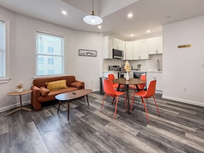 Relax in this stylish living space with a brown leather sofa, round coffee table, and dining area with four chairs.