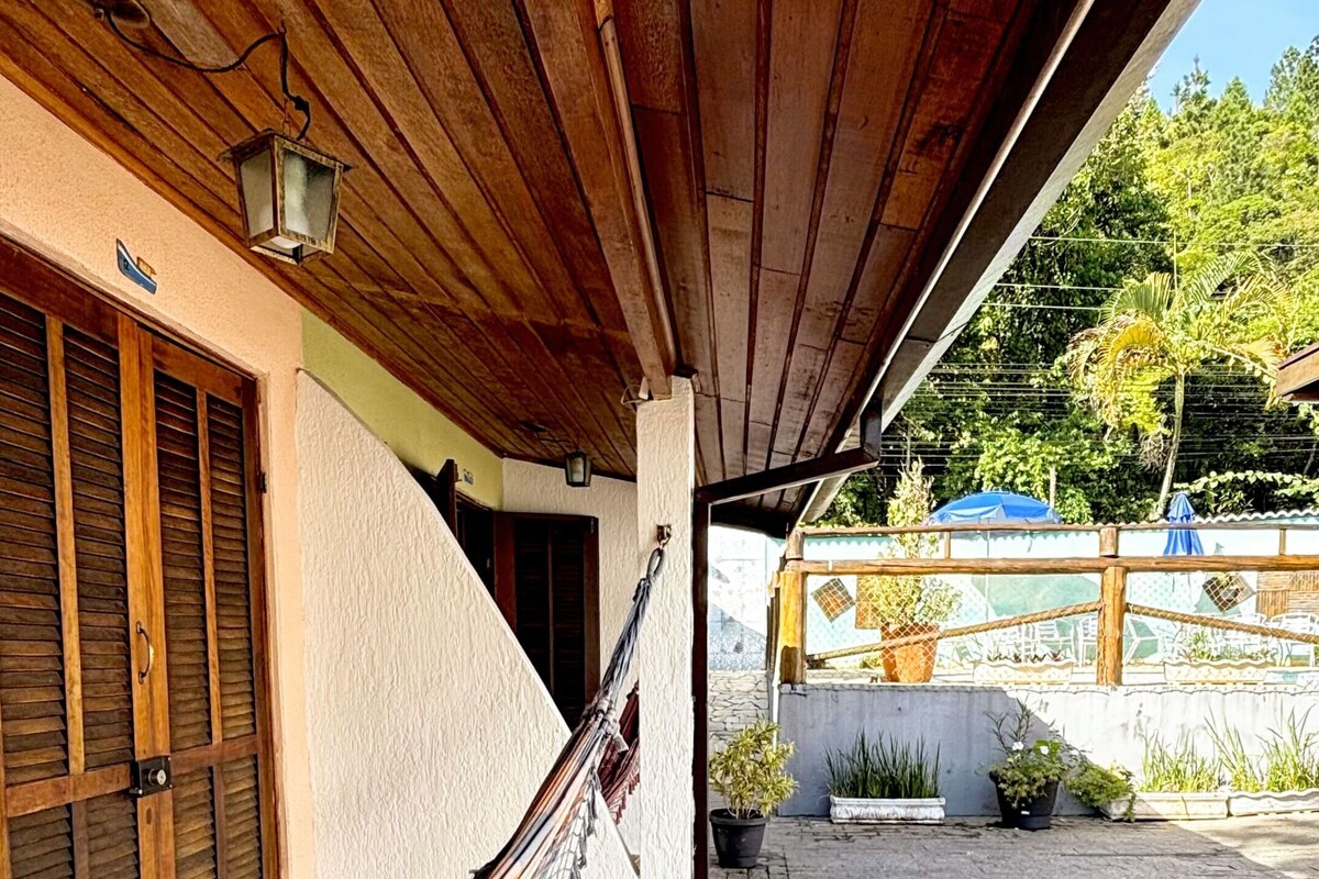 Un espace extérieur abrité, doté d’un sol carrelé, d’un hamac et d’un plafond en bois.