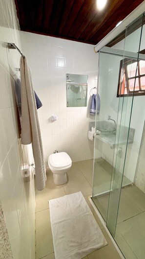 Een badkamer met een douchecabine van glas, een toilet, een wastafel en een spiegel.