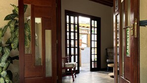 A wooden door with a glass panel, a blue mat with text, and a plant to the left. - Pousada Sr Marinheiro Ubatuba (Ubatuba)