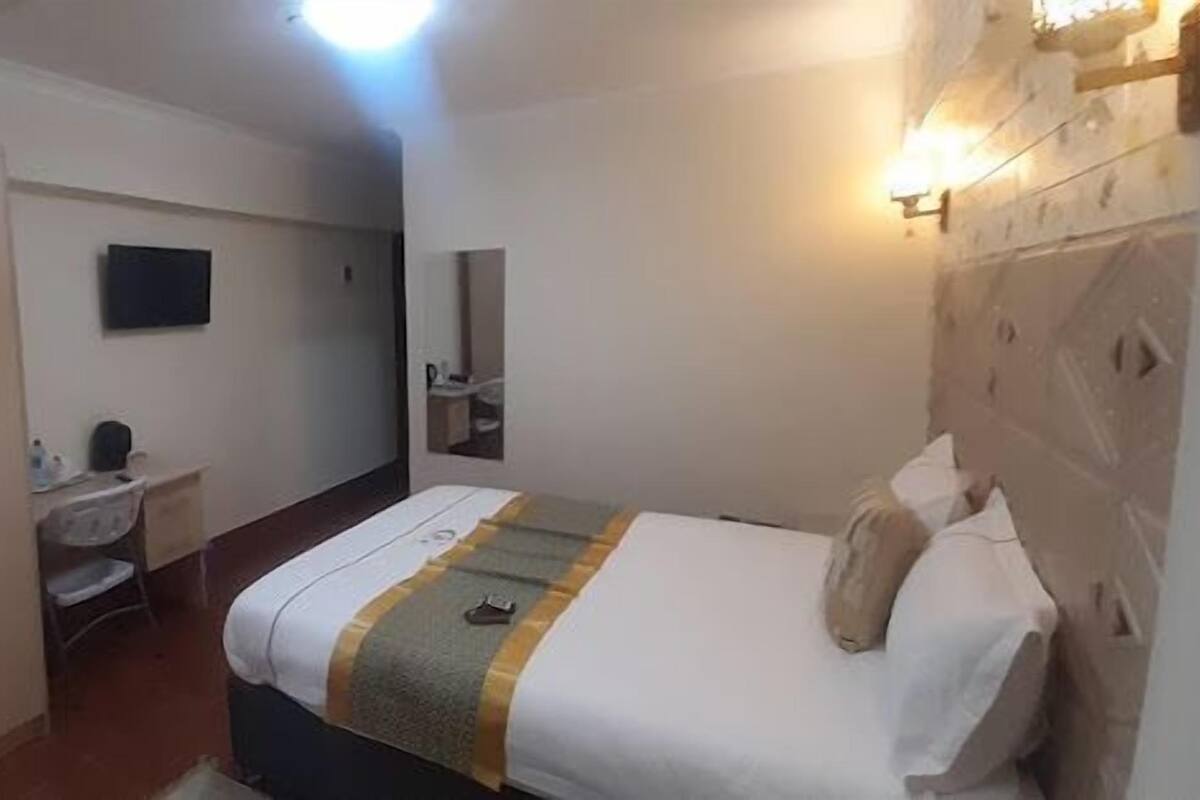 A compact hotel room with a bed, a desk, a chair, and a wardrobe.