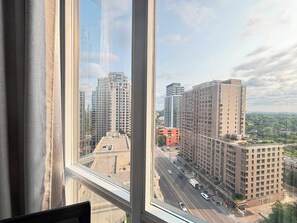 A view from a window overlooking a cityscape with high-rise buildings and a road.
