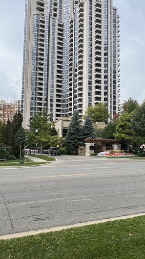 A tall residential building with multiple balconies and a gated entrance.