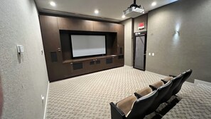Een bioscoopzaal met een groot scherm, comfortabele zitplaatsen en een vloerbedekking.