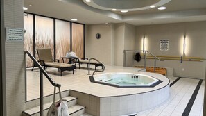 Een wellnessruimte met een whirlpool, zitplaatsen en een waarschuwingsbord.