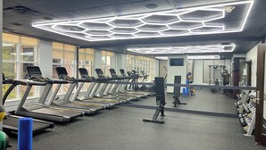 Una palestra con tapis roulant, attrezzature per esercizi e un grande specchio.