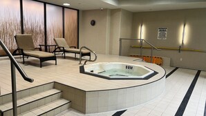 Area piscina con idromassaggio, sedie e cartello di avvertimento.