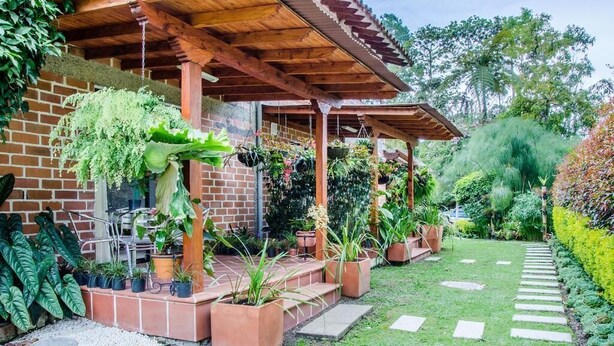 Un patio cubierto con plantas en macetas y una pared de ladrillo.