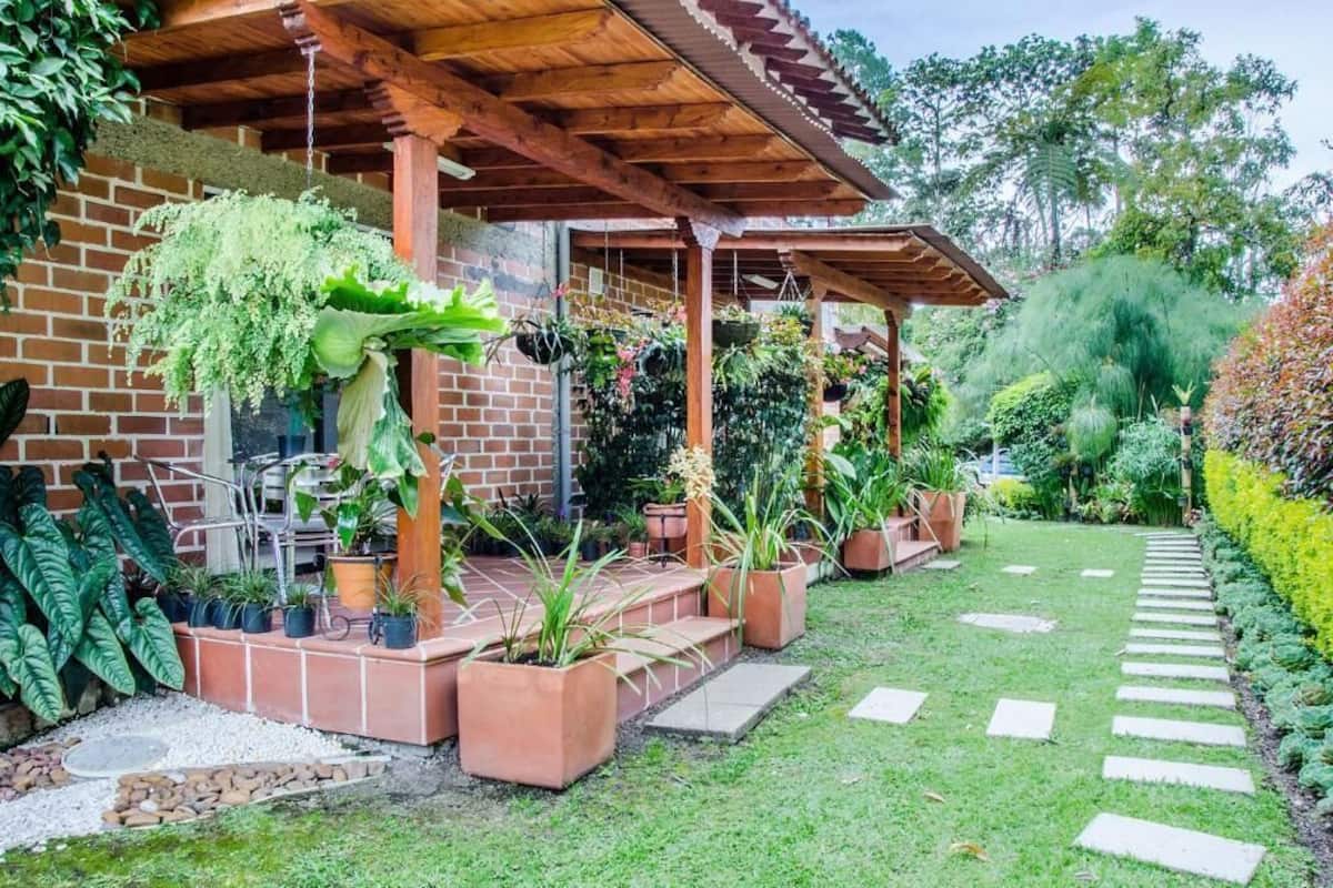 A covered patio area with potted plants and a brick wall.