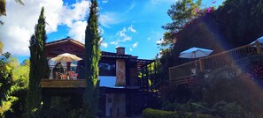A patio area with outdoor seating, a wooden deck, and a stone building with a tiled roof. - Hotel Campestre La Martina (Rionegro)