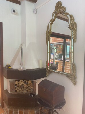 A corner of a room with a fireplace, a mirror with an ornate frame, and a small wooden cabinet. - Hotel Campestre La Martina (Rionegro)