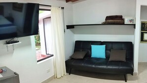 A hotel room with a bed, a sofa, a TV, and a painting on the wall. - Hotel Campestre La Martina (Rionegro)