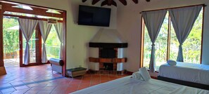 A room with a fireplace, a bed, a TV, and a balcony with curtains. - Hotel Campestre La Martina (Rionegro)