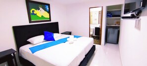 A hotel room with a bed, a nightstand, a TV, and a door leading to a bathroom. - Hotel Campestre La Martina (Rionegro)