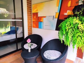A corner with two wicker chairs, one with a pink rose, and a large green plant. - Hotel Campestre La Martina (Rionegro)