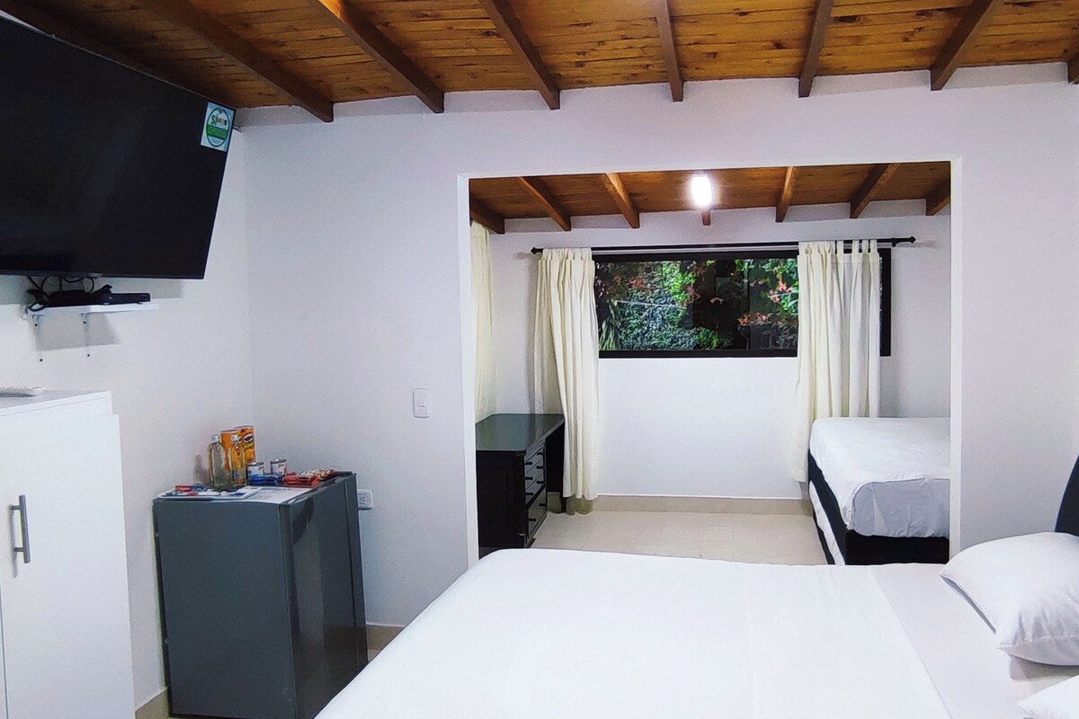 Una camera da letto con un letto, una TV, una scrivania e una finestra con tende.