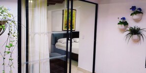 A bedroom with a bed, a glass door, and a wall-mounted plant. - Hotel Campestre La Martina (Rionegro)