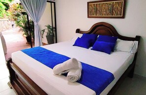 A neatly made bed with blue and white bedding, a wooden headboard, and a rolled towel on the bed. - Hotel Campestre La Martina (Rionegro)