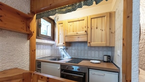 A compact kitchen with wooden cabinets, a sink, a stove, and a dishwasher. - Apartment Erica Bormio (Bormio)