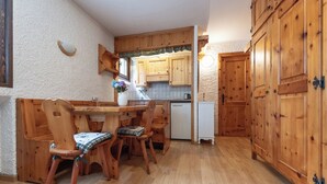 A wooden dining table with chairs, a white refrigerator, wooden cabinets, and a kitchen area with wooden countertops and cabinets. - Apartment Erica Bormio (Bormio)
