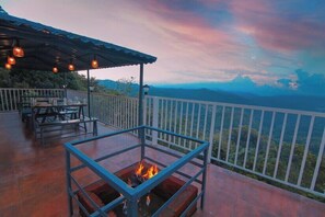 A terrace with a fire pit, outdoor seating, and a scenic view of the mountains. - Bright Meadow Dam View Resort (Devikolam)