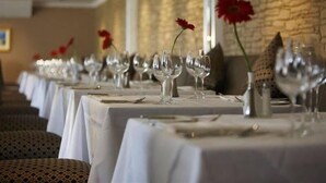 A row of tables set for dining with white tablecloths, clear glassware, and red flowers. - Portmarnock Hotel And Golf Links (Portmarnock)