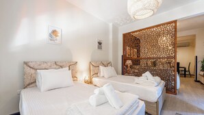 Ein Hotelzimmer mit zwei Betten, einem dekorativen Raumteiler und einer Kristallleuchter.