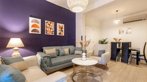 Ein Wohnzimmer mit grauem Sofa, einem weißen Sessel, einem runden Couchtisch und einer Deckenleuchte.