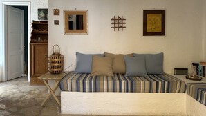 Une pièce chaleureuse avec un canapé à rayures, un meuble en bois, un miroir et un tableau encadré accroché au mur.