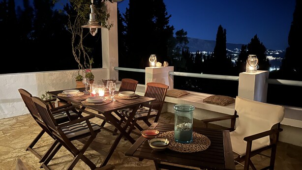 Un espace de restauration en plein air avec une table dressée pour quatre personnes, entourée de chaises, et protégé par un auvent.
