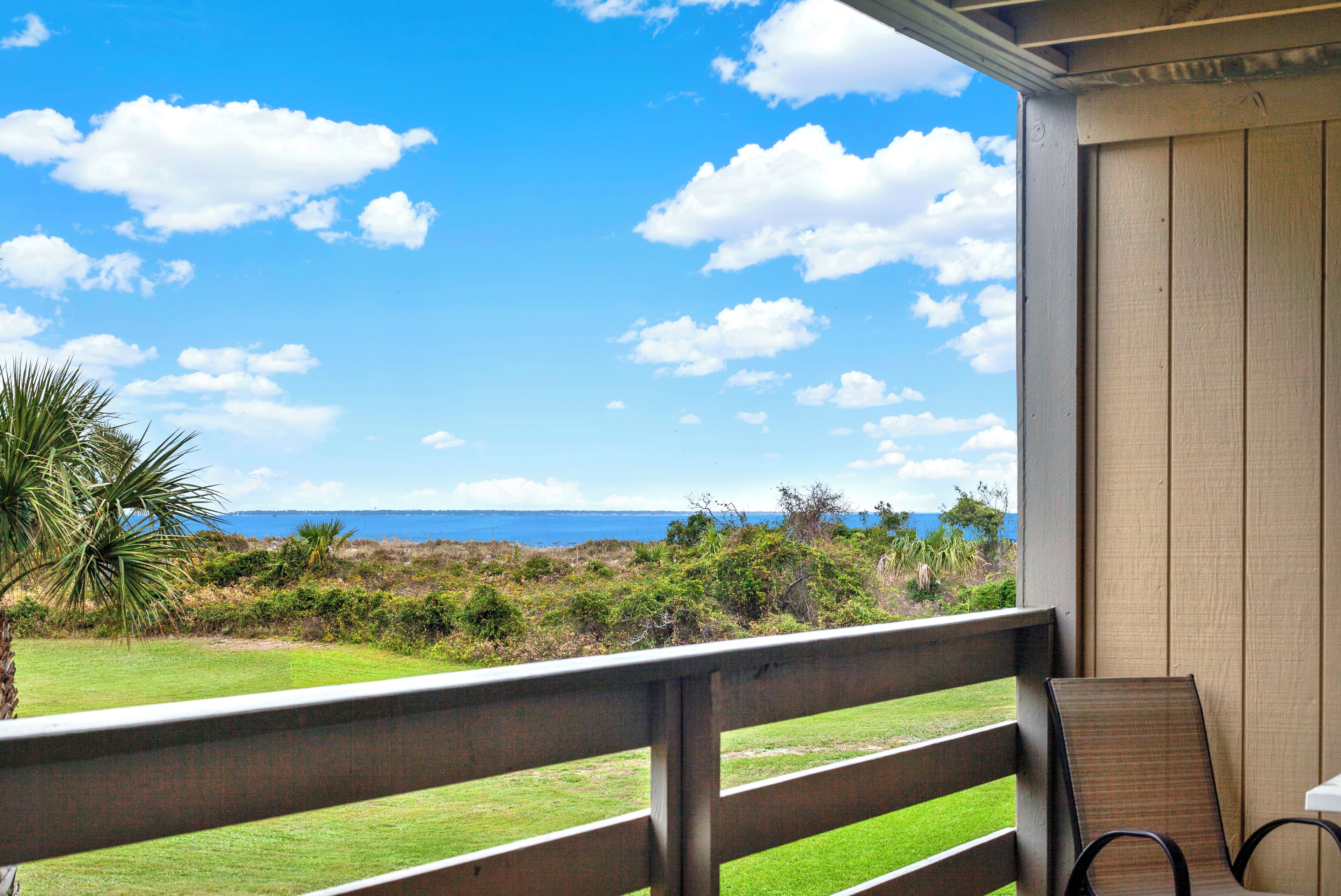 Un balcon avec vue sur l’océan et un espace verdoyant.