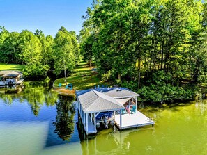 A floating dock with a covered seating area, a flag, and a small boat docked nearby. - Lakefront Lake Anna, Fire Pit, Pool, Beach (Mineral)