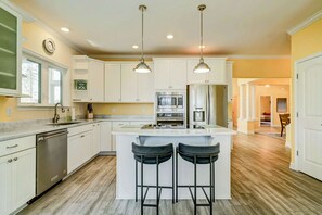 A modern kitchen with white cabinets, a central island with bar stools, stainless steel appliances, and pendant lighting. - Lakefront Lake Anna, Fire Pit, Pool, Beach (Mineral)