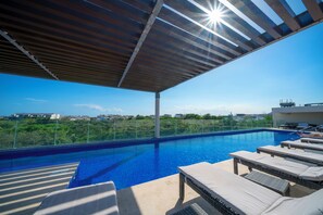 A rooftop swimming pool with lounge chairs and a pergola. - 2 BR Condo with Rooftop Pool - Terrazas (Playa del Carmen)
