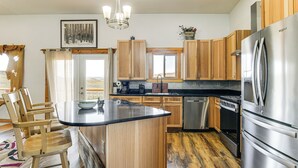 Una cocina con armarios de madera, un refrigerador de acero inoxidable, un horno empotrado y una ventana con vistas panorámicas.