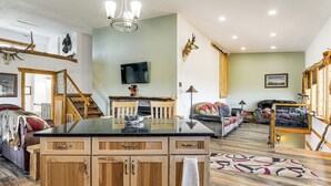 Un salón espacioso con una mesa de comedor de madera, un sofá y un televisor montado en la pared.