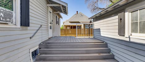 Traditional home with a front entrance, featuring a wooden staircase and windows on either side.