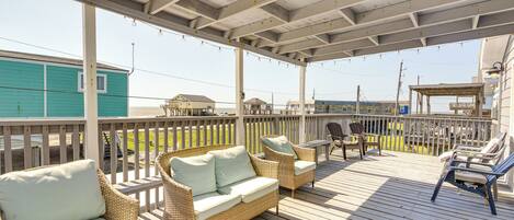 A covered outdoor deck with wicker furniture, a table, and chairs.