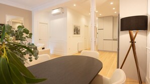A modern hotel room with a dining table, white chairs, a potted plant, and a floor lamp. - Luxury in downtown Madrid. (Madrid)