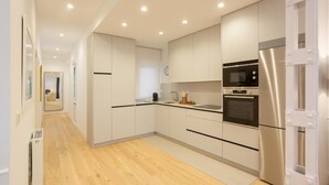 A modern kitchen with white cabinets, stainless steel appliances, and a wooden floor. - Luxury in downtown Madrid. (Madrid)
