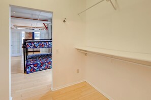 A room with a bunk bed, wooden flooring, and a white wall.