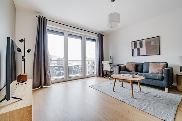 Un salon moderne avec un canapé, une table basse et une grande fenêtre avec des rideaux.